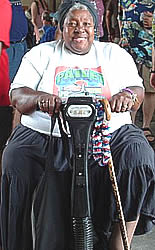 Photo:Woman on scooter, smiling as she makes her way around a festival.